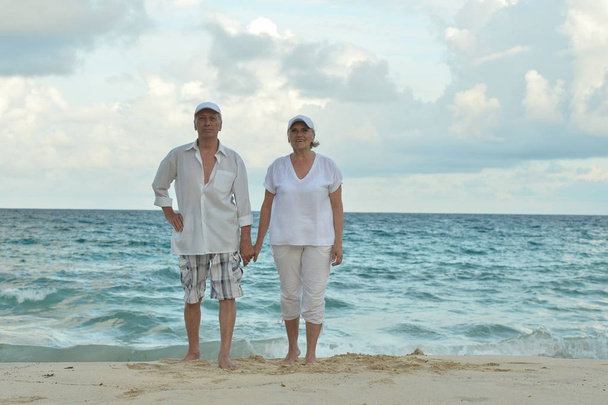 Счастливая пожилая пара, гуляющая по тропическому пляжу
  - Фото, изображение