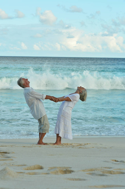 Gelukkig bejaarde echtpaar rustend op tropisch strand  - Foto, afbeelding