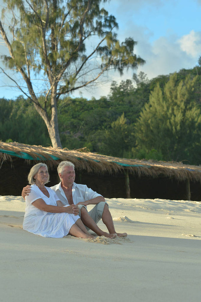 Feliz pareja de ancianos sentados en la playa tropical
  - Foto, Imagen