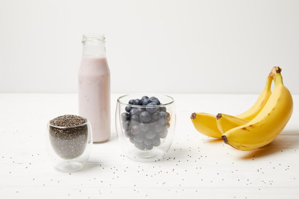 close up view of ingredients for chia pudding dessert with blueberries and bananas on white wooden surface - Photo, Image