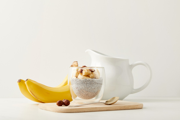 vista de perto do saboroso pudim de semente de chia com bananas e avelãs na mesa branca
 - Foto, Imagem