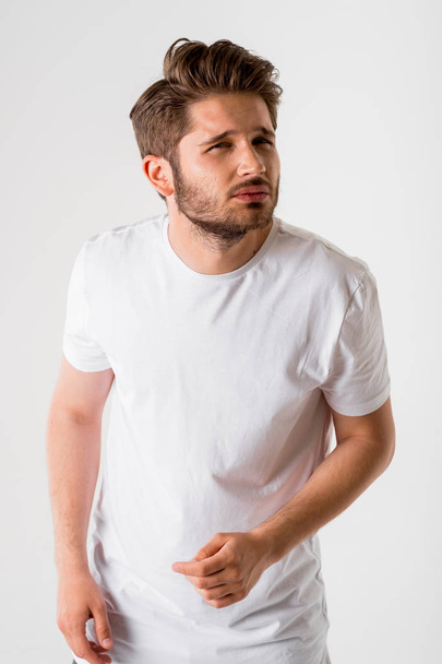 portrait of young suspicious bearded man in white shirt on grey background  - Fotó, kép
