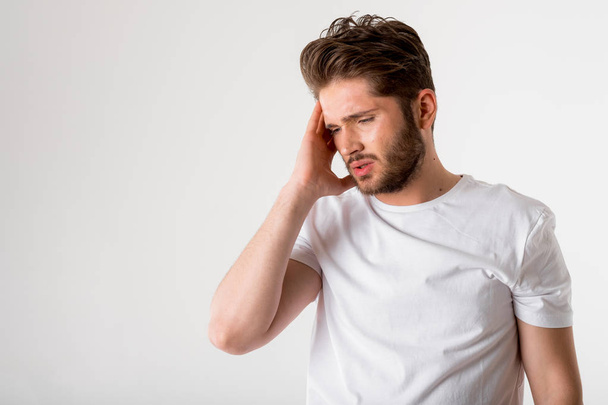 portrait of young bearded man in white shirt have headache on grey background - Фото, изображение