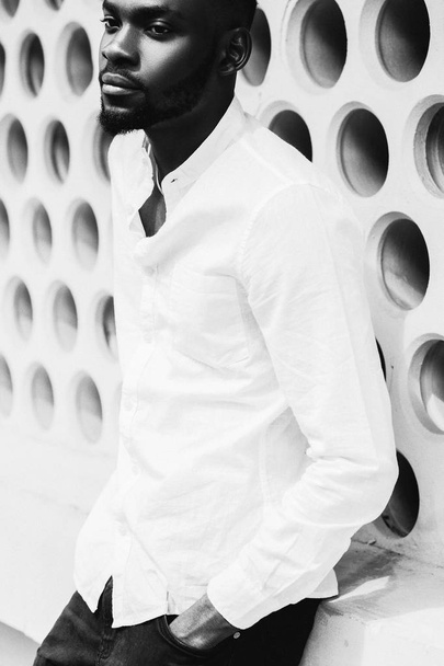 Portret van casual afro Amerikaanse man die met handen in zak in studio op witte achtergrond - Foto, afbeelding