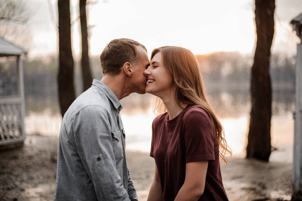 Couple in love standing face to face and laughing on the background of lake - Foto, Bild