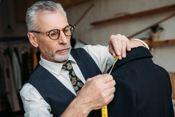 guapo sastre senior chaqueta de medición con cinta métrica en taller de costura
 - Foto, Imagen