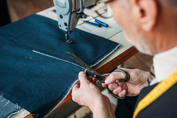 bijgesneden afbeelding van senior op maat snijden doek op naaien workshop - Foto, afbeelding