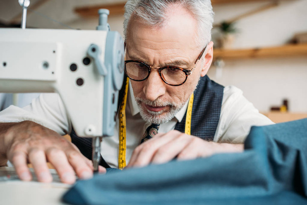 paño de costura sastre guapo serio con máquina de coser en taller de costura
 - Foto, Imagen