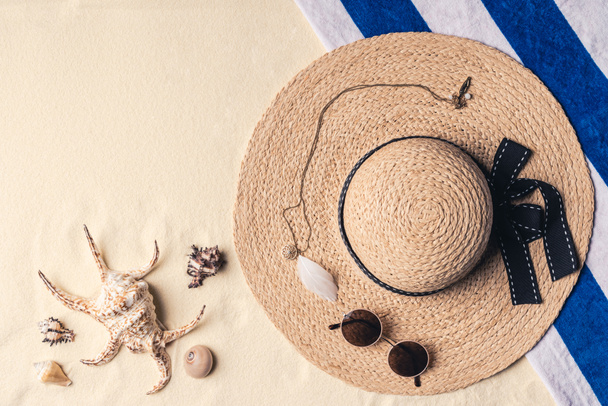 Straw hat with sunglasses and seashells on sandy beach - Zdjęcie, obraz