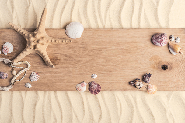 Summer travel template with seashells on wooden pier on light sand - Photo, Image