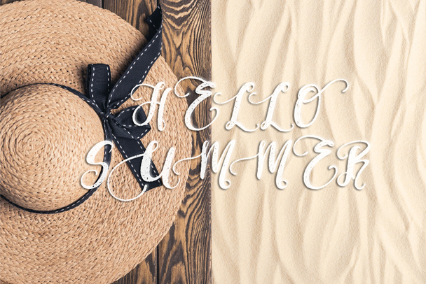 Stro hoed op houten pier aan zandstrand met Hallo zomer inscriptie - Foto, afbeelding