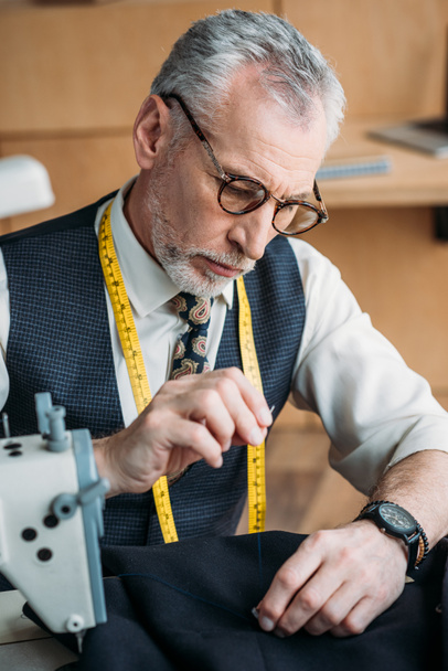 handsome tailor sewing button to jacket at sewing workshop - Φωτογραφία, εικόνα