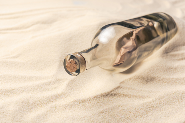 Corked bottle with message on sandy beach - Fotó, kép