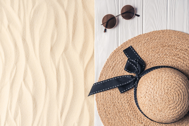 Strohhut und Sonnenbrille auf hellem Sand - Foto, Bild