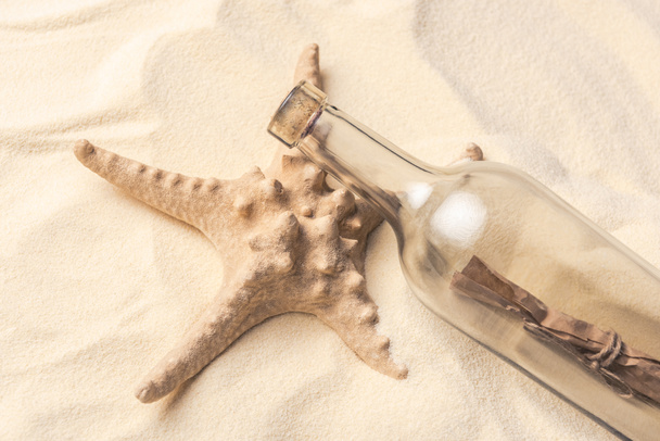Starfish and bottle with letter on light sand - Photo, Image