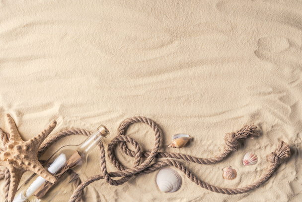 文字と光の砂の上にロープで殻付きボトル - 写真・画像