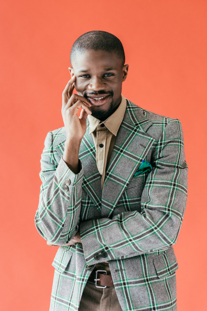 handsome smiling african american man posing in vintage jacket, isolated on red - Valokuva, kuva