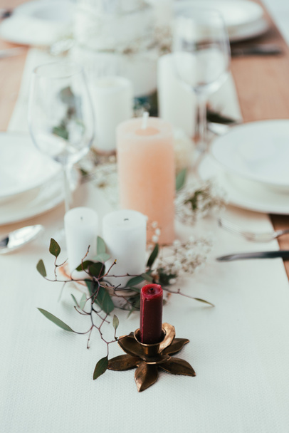 close up view of stylish table setting with candles, wineglasses and eucalyptus for rustic wedding - Photo, Image