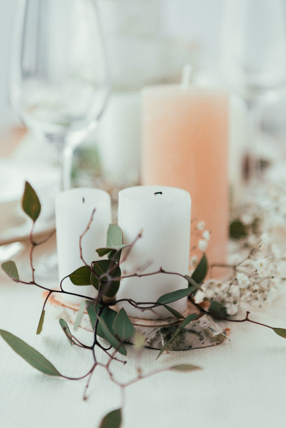 Nahaufnahme der stilvollen Tischdekoration mit Kerzen, Blumen und Eukalyptus für eine rustikale Hochzeit - Foto, Bild