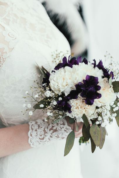 частковий вид на наречену в білій сукні з красивим весільним букетом в руках
 - Фото, зображення
