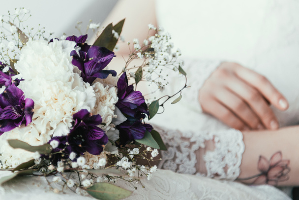 partial view of bride in white dress with beautiful bridal bouquet - Fotó, kép