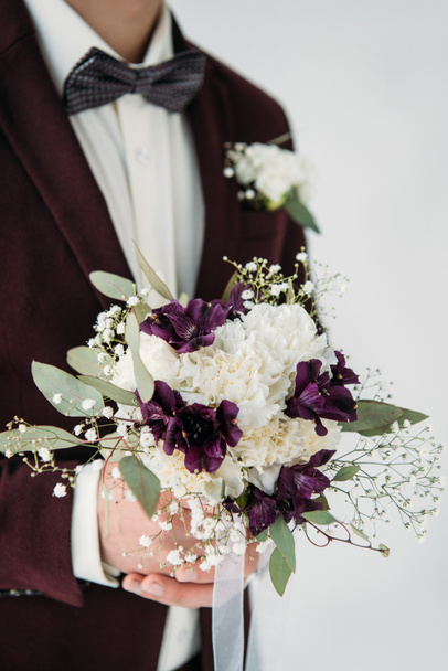 partial view of groom in suit with beautiful wedding bouquet in hands - Fotó, kép