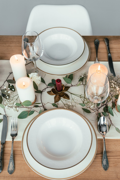 close up view of stylish table setting with candles, empty wineglasses and plates for rustic wedding - Photo, Image