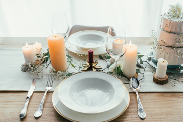 κλείνω πάνω θέα της ρύθμισης κομψό τραπέζι με κεριά, wineglasses και γαμήλια τούρτα για το γάμο ρουστίκ - Φωτογραφία, εικόνα