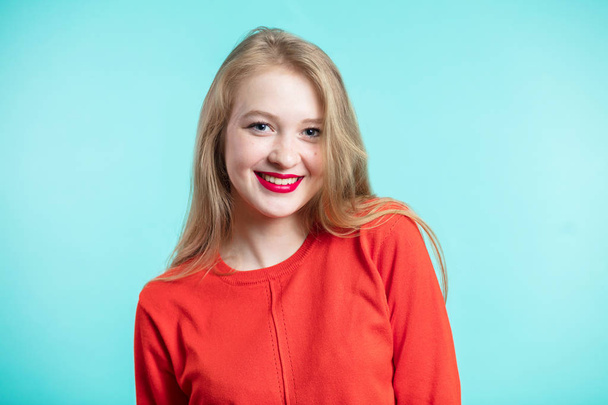Smiling happy woman on blue background. Redheaded girl in red dress and red lips. Positive emotions, youth - Foto, Imagem