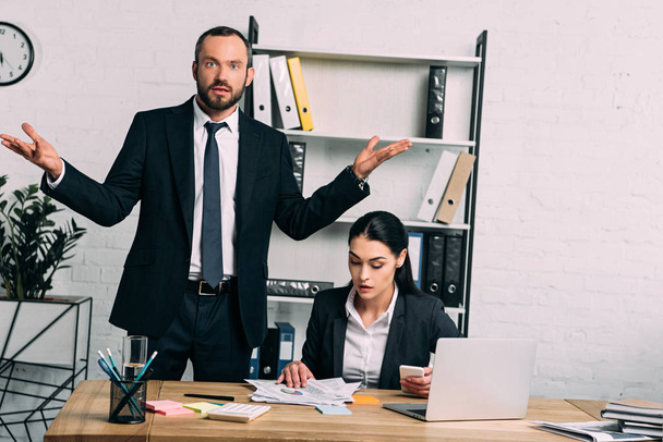портрет стресса бизнесмена и сфокусированного коллеги, работающего на рабочем месте с ноутбуком в офисе
 - Фото, изображение