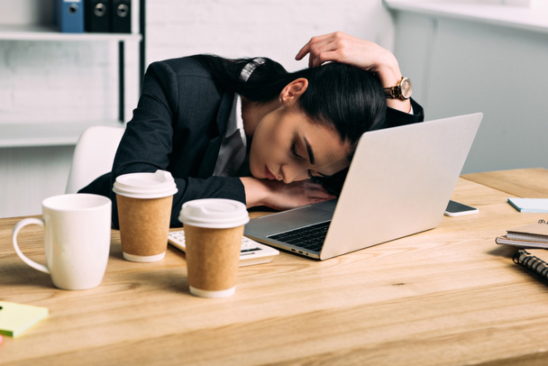 donna d'affari oberata di lavoro che dorme sul posto di lavoro con computer portatile e caffè per andare in ufficio
 - Foto, immagini