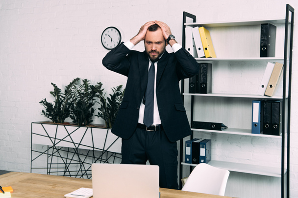 portrait of stressed businessman in suit standing at workplace in office - Foto, Imagen