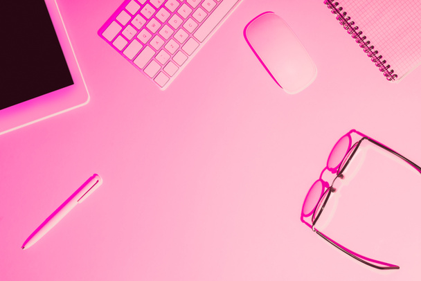 immagine tonica rosa di penna, tablet digitale, occhiali, libro di testo, tastiera del computer e mouse sul tavolo
  - Foto, immagini