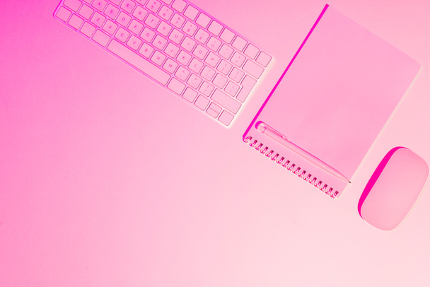 pink toned picture of pen, empty textbook, computer keyboard and mouse on table  - Фото, изображение