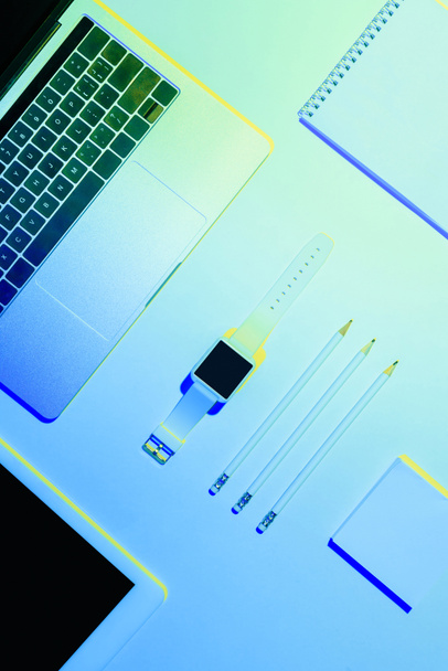 kék tónusú kép, a laptop, digitális tabletta, smartwatch, ceruzák, tankönyv és ragadós jegyzék  - Fotó, kép