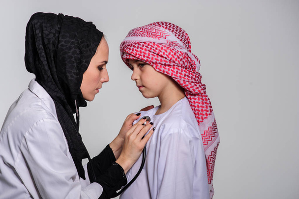 Arabialainen sairaanhoitaja ja pieni muslimipotilas terveydenhuollon kanssa
. - Valokuva, kuva