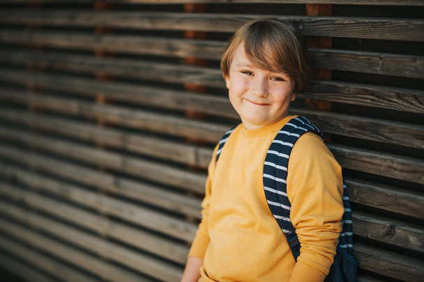 Retrato al aire libre de niño lindo con sudadera amarilla y mochila. Regreso al concepto escolar
 - Foto, imagen