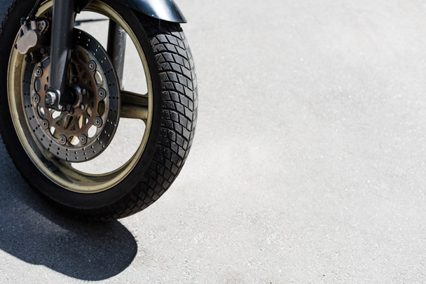 Rueda delantera con neumático negro de motocicleta en la calle
 - Foto, Imagen