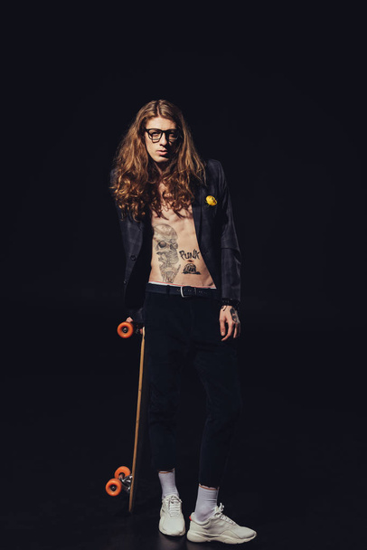 tattooed shirtless man posing with skateboard, isolated on black - Photo, Image