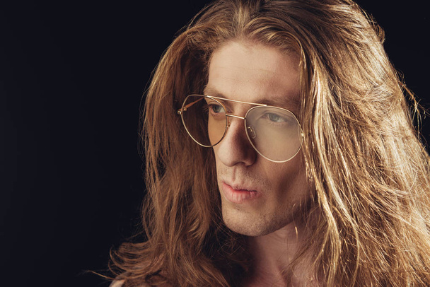 portrait of stylish man with long hair in stylish glasses, isolated on black - Фото, изображение