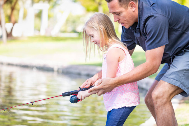 Nuori valkoihoinen isä ja tytär ottaa hauskaa kalastusta järvellä
. - Valokuva, kuva