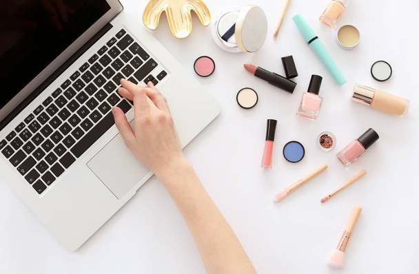 Young woman with makeup products using laptop at table. Beauty blogger - Foto, imagen