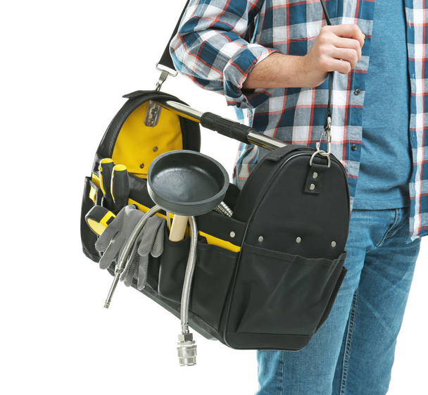 Young plumber with tool bag on white background, closeup - Foto, afbeelding