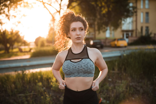 Joven mujer en forma en ropa deportiva preparándose para comenzar a correr al aire libre
 - Foto, imagen