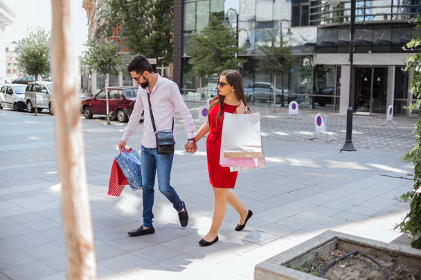 Couple with shopping bags holding hands in the city - Foto, imagen