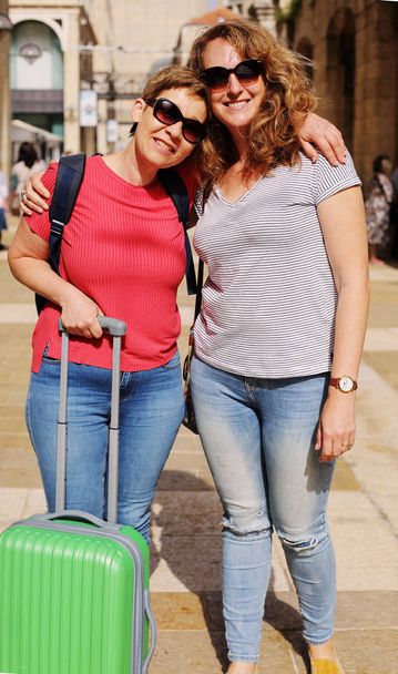 portrait of happy mature women posing with luggage at sunny street - Photo, Image