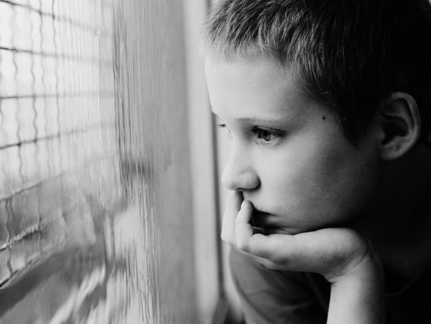 cute ten years old autistic boy looking at rain, black and white  - Foto, Bild
