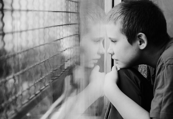 söpö kymmenen vuotta vanha autistinen poika katselee sade, musta ja valkoinen
  - Valokuva, kuva