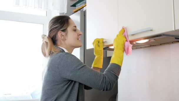 4 k βίντεο χαμογελώντας νεαρή γυναίκα σε λατέξ γάντια καθαρισμού ντουλάπια στην κουζίνα με πανί - Πλάνα, βίντεο