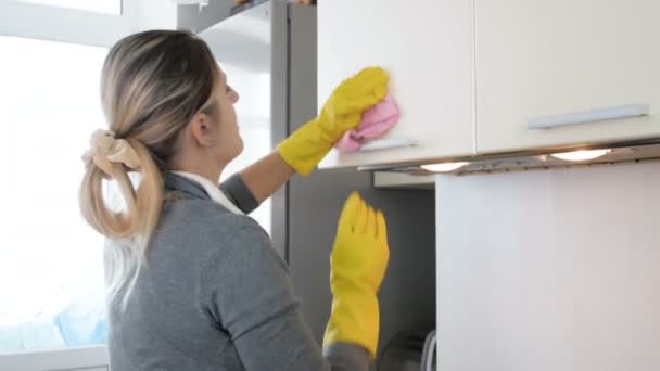 4 k wideo młoda gospodyni do polerowania i czyszczenia szafki w kuchni - Materiał filmowy, wideo